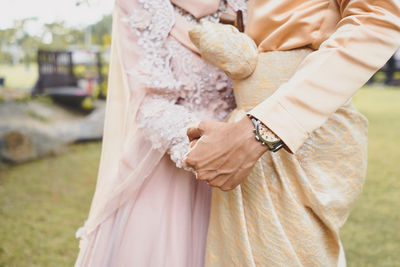 Midsection of bride and bridegroom standing outdoors