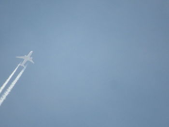 Low angle view of airplane flying against clear blue sky