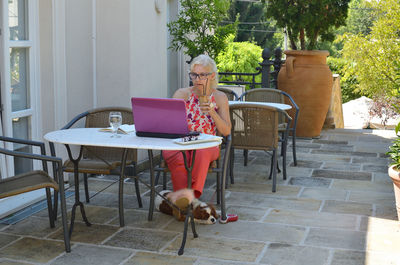 Woman on vacation casually but elegantly dressed working on a laptop and drinking coffee