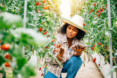 Young woman wearing hat standing amidst plants