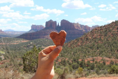 Midsection of person holding mountain against sky