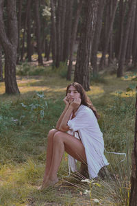 Full length woman sitting in forest