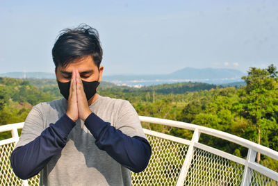 Young man looking at camera against sky