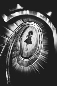 High angle view woman lying down on floor seen through spiral staircase