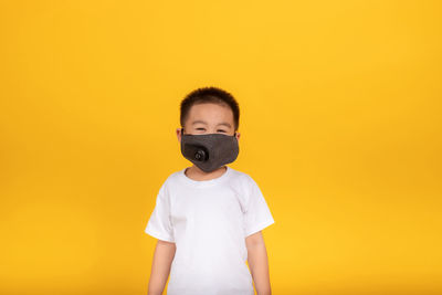 Portrait of boy standing against yellow background