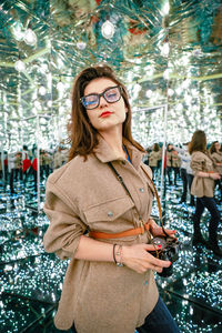 Young woman with camera in mirror maze