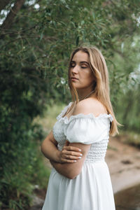 Portrait of young woman standing against plants
