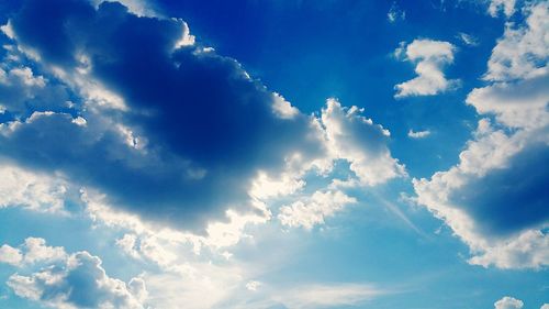 Low angle view of sunlight streaming through clouds