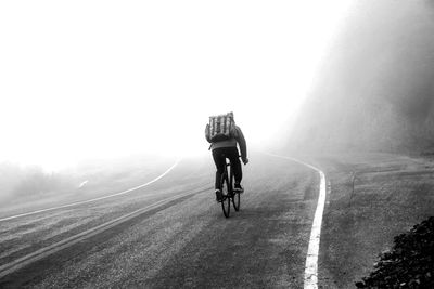 Rear view of man riding bicycle on road