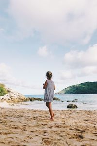 Rear view of man standing on beach against sky