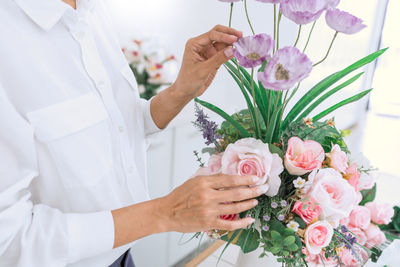 Midsection of woman touching bouquet in flower shop