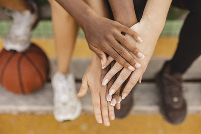 Multiracial friends stacking hands in sports court