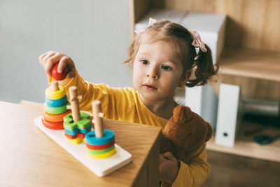 Portrait of cute girl sitting on table at home