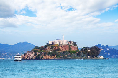 View of sea and buildings against cloudy sky