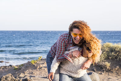 Female friends playing against sea