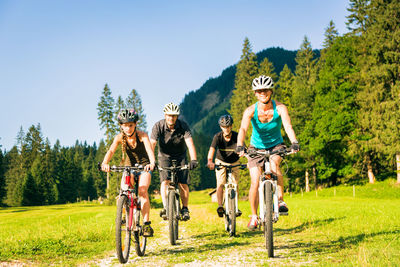 Family cycling on field against sky