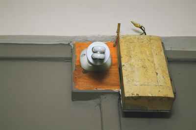 Low angle view of light bulb with door bell on gray wall