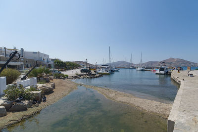 Sailboats moored in harbor against clear sky