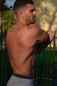 Midsection of shirtless man standing outdoors