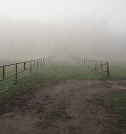 Fence in foggy weather against sky during winter