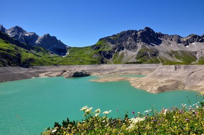 Scenic view of lake and mountains against clear blue sky