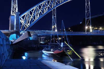 Illuminated bridge over river against clear sky at night