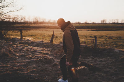 Man standing on field against sky during sunset