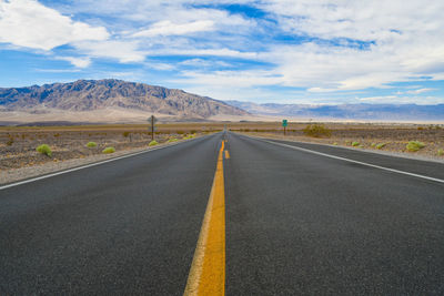 Empty road by mountains against sky