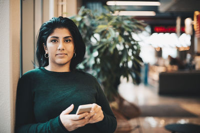 Portrait of confident businesswoman holding smart phone in office