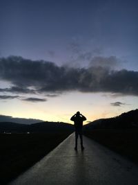 Rear view of man photographing on road against sky