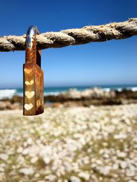 Close-up of padlock on beach against sky