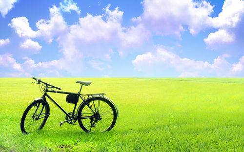 Bicycle parked on field against sky