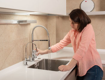 Side view of woman washing hands in bathroom