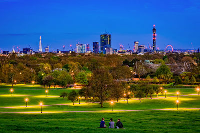 People in illuminated park against blue sky