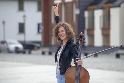 Portrait of smiling woman holding violin on street