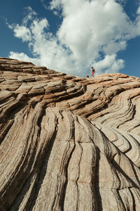 Female hiker and dog walk the ridge line of red slick rock in utah