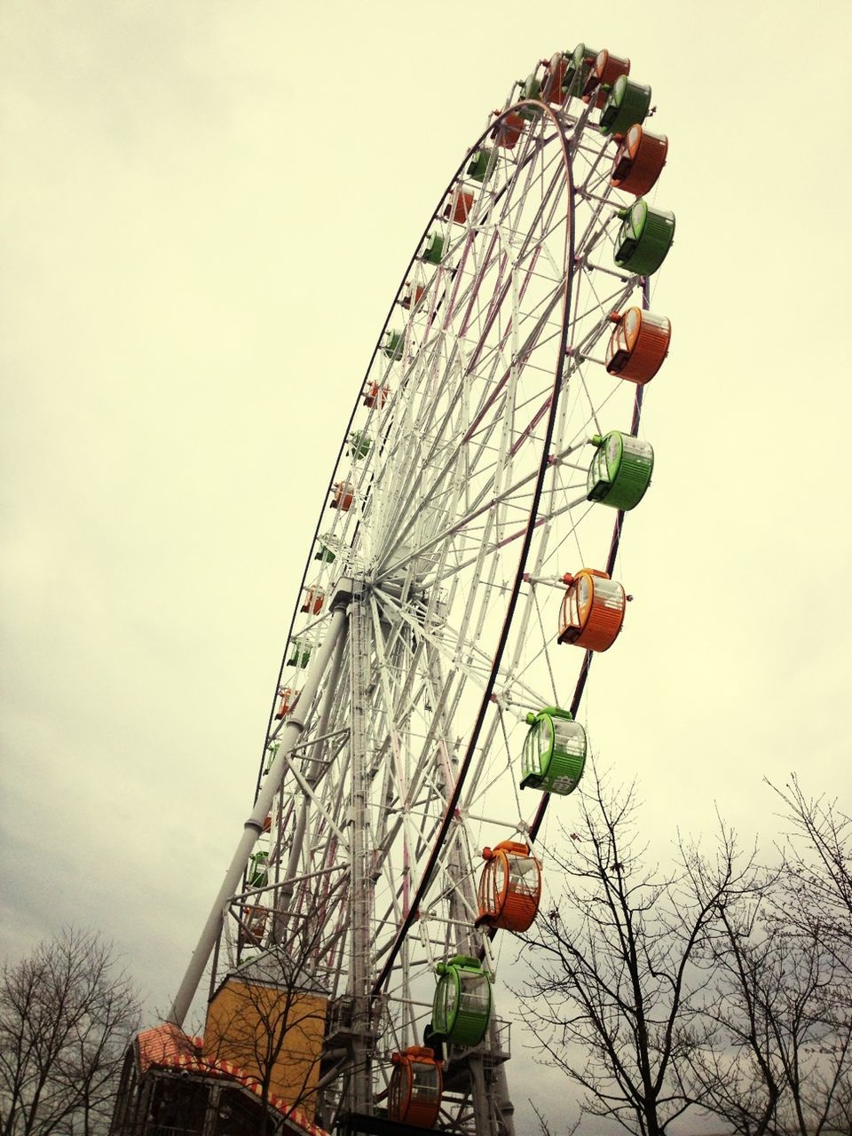 amusement park ride, amusement park, ferris wheel, arts culture and entertainment, low angle view, built structure, sky, architecture, fun, enjoyment, fairground, fairground ride, outdoors, day, travel destinations, chain swing ride, tree, clear sky, big wheel, metal