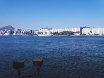 View of buildings in sea against clear blue sky