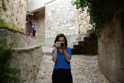 Woman photographing while standing on wall