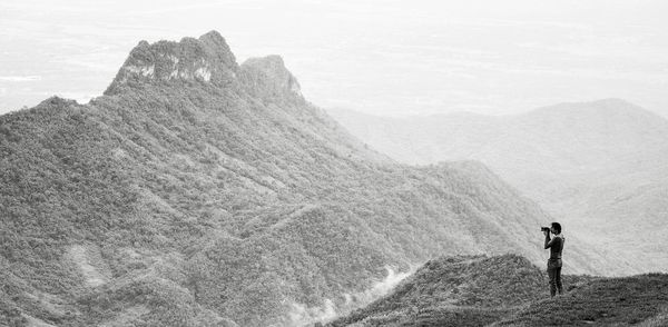 Man photographing mountains during foggy weather