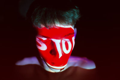 Close-up of shirtless man with light on face against black background