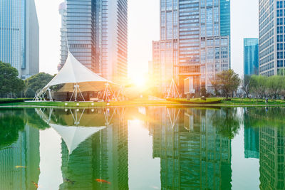 Reflection of buildings in lake against sky in city