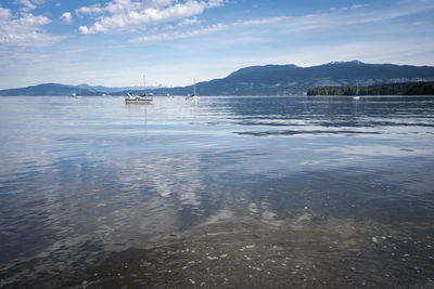 Calm sea with boats and mountains in backdrop, shot in vancouver, british columbia, canada