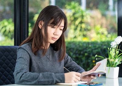 Young woman looking away while sitting on table