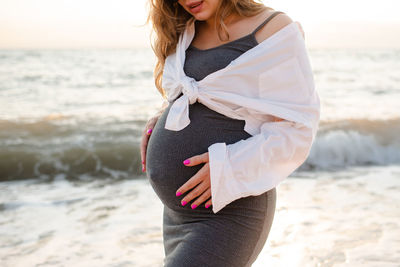 Pregnant woman wear casual dress and shirt over sea nature background outdoor.