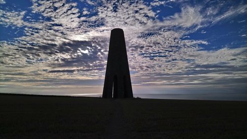 Low angle view of cross on field against sky during sunset