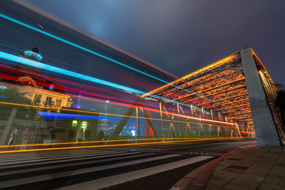 Light trails on bridge in city against sky at night