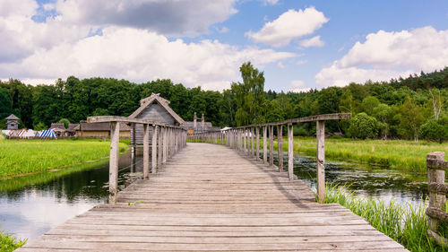 Footbridge over lake against sky