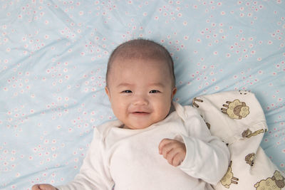 Portrait of cute baby girl lying on bed