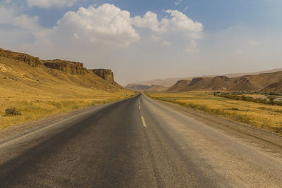 Road leading towards mountains against sky